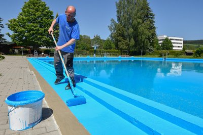 Letzte Vorbereitungen vor dem Saisonstart im Olbernhauer Freibad: Schwimmmeister Markus Schubert streicht die Fußlaufrinne am Beckenrad.