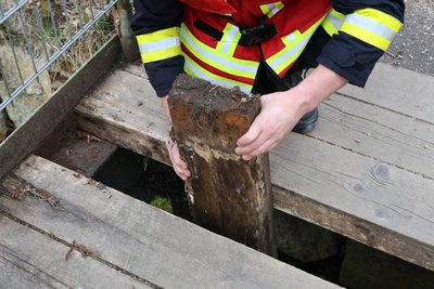Eine der Holzplanken des Brückenbelags ist durchgefault und eingebrochen.