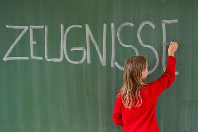 Eine Viertklässlerin schreibt in einer Grundschule das Wort „Zeugnisse“ auf eine Tafel.