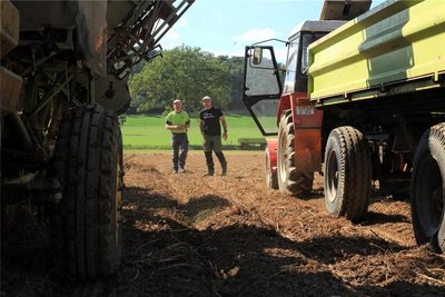 Christian Kluge-Sammer und Robert Sammer verfolgen die Ernte der Kartoffeln. Ein Traktor zieht den Roder, der andere den Hänger. l