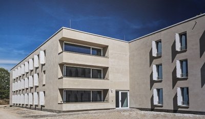 Die Fassade des Bayernkollegs Augsburg ist schlicht und modern. Doch mit der speziellen Oberflächenstruktur des Waschputzes haben die Architekten und die bauausführenden Firmen die Jury des europaweiten Fassadenwettbewerbs überzeugt. 