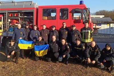 Fahrzeugübergabe in Chelm: Der Herr hinten in der Mitte mit Mütze ist Olexandr Pylypenko, Chef des Katastrophenschutzes in Solotonoscha. Vor ihm kniend: Sachsens Landesfeuerwehrschulleiter Markus Morgenstern.