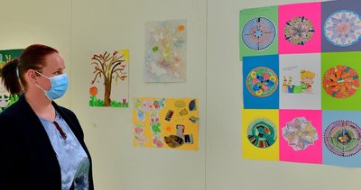 DRK-Mitarbeitrein Doreen Kums schaut sich im Impfzentrum in Mittweida eine Wand an, die mit Kinderbildern gestaltet wurde. 