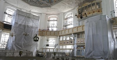 Weil das Bohren für die neuen Anker im Mauerwerk nur trocken erfolgen kann, wurden Altar, Kanzel und die Orgel mit einem atmungsaktiven Vlies verhüllt, um den Staub abzuhalten. 
