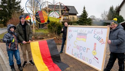 Selbst gebaute Olympische Ringe, die deutsche Fahne und ein Glückwunschschild: Jens Rach, Mirko Braun, Theo Völckel und Benjamin Braun (v. r.) haben sich für Erik Simon und Candy Bauer einiges einfallen lassen.