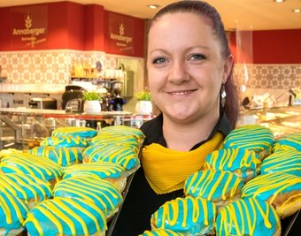 Verkäuferin Susann Reimann präsentiert in den ukrainischen Nationalfarben glasierte Pfannkuchen. 