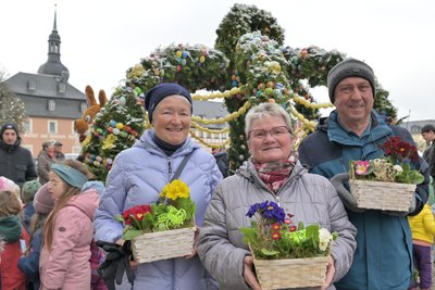 Gisela Feulner, Irmgard Schindler und Roland Feulner haben sich beim Schmücken des Osterbrunnens in Zwönitz engagiert – dafür gab es am Freitag ein blühendes Dankeschön.