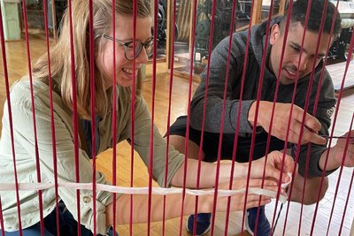 Viele Hände weben zusammen ein Haus: Mitmachaktion der Schauweberei.