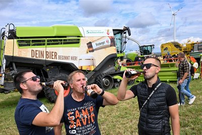 Andreas Wirth, Uwe Irmscher und Benjamin Irmscher genießen ein Bier vor dem sogenannten „Biermähdrescher“. Ohne dessen Arbeit wären die Flaschen der drei Männer leer geblieben.