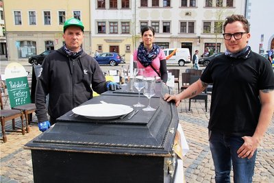 Sanja Koch, Maika Kreller und Jens Hennig (v. l.) an dem mit Geschirr gedeckten Sarg. 