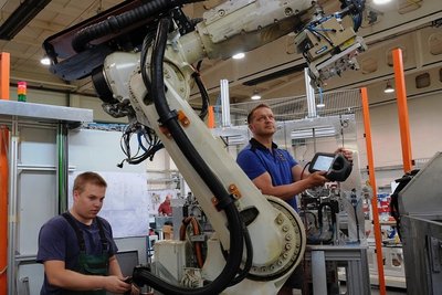 Thomas Alte programmiert einen Roboter, der bei der Porsche-Zylinderkopfbearbeitung eingesetzt wird, links Mechatronik-Lehrling Philipp Henniger.