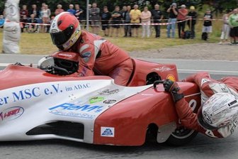 220 Starter heizen über Traditionskurs - Tiefer geht es kaum noch: Richtig nah kommen die Beifahrer in den Gespannen dem Asphalt auf dem Zschorlauer Dreieck - im Bild oben schwebt Mario Reinwardt aus Raschau mit Co-Pilot Knut Rottloff aus Crottendorf in einer Honda Derbyshire von 1977 über den legendären Rundkurs. Diese Sonderklasse bereichert den Classic-Grand-Prix ungemein. Ansonsten ziehen bei dem Spektakel vor allem historische Rennmotorräder die Blicke auf sich. Das 26. Mal geht es am kommenden Wochenende rund. 