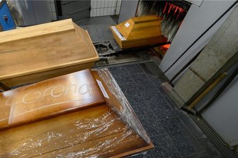 23 Corona-Todesfälle binnen einer Woche im Vogtlandkreis - Mit Kreide geschrieben steht "Corona" auf einem Sarg mit einem Verstorbenen, der an oder mit dem Coronavirus gestorben ist, vor dem Einäscherungsofen eines Krematoriums.