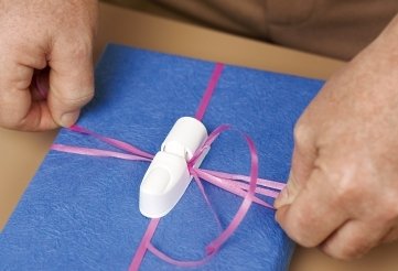 Der Einpackdaumen der Firma Donkey Products ist eine Plastikklammer, die den Knoten des Geschenkpapiers halten kann.