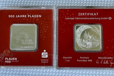 Der quadratische Silberbarren hat die Motive der Medaille übernommen. Eine Seite zeigt das Logo der Stadt Plauen zum 900. Stadtjubiläum, auf der anderen Seite ist die Plauener Johanniskirche zu sehen. 