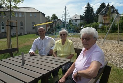 Michael Kropff, Pastor der Evangelisch-methodistischen Kirche in Zschorlau (li.) hat sich mit Irmtraud Friedrich (Mitte) und Helga Meier zusammengesetzt. Die beiden Bewohnerinnen des Seniorenparks genießen das schöne Wetter im neu gestalteten Kirchengarten. 