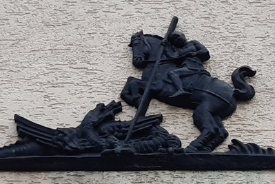 Detail über dem Eingang: Ritter Georg und Drache aus dem Stadtwappen. Die auf Simsen links und rechts geplanten Statuen wurden nie realisiert.