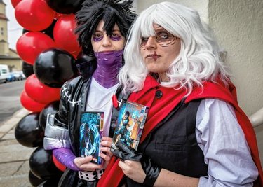 "Shimara" (links) und "Bella exd" stehen mit dem Manga-Comic "My Hero Academia", das als Vorbild für ihre Cosplays dient, vor dem neu eröffneten "Mangapoint" an der Chemnitzer Schloßstraße. 