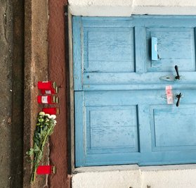 Vor der Haustür liegen Blumen. 