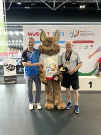 Gemeinsam im Oman an der Platte: Wolfgang Schmidt (r.) und Sohn Andreas, hier mit dem WM-Maskottchen, einer Sandkatze, haben bei der Senioren-WM in Omans Hauptstadt Maskat aufgeschlagen. 