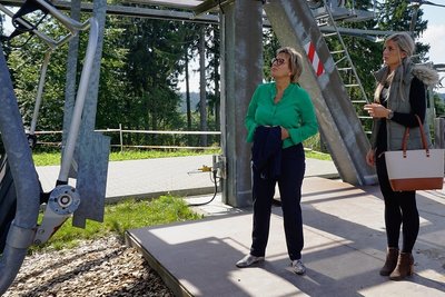 Staatsministerin Barbara Klepsch (links) lässt sich von DLT-Geschäftsführerin Jennifer Braun die Sommernutzung des Vierer-Sessellifts für die Bikewelterklären.