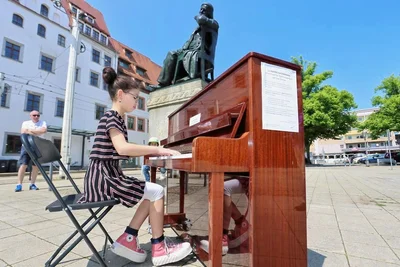 Am Schumanndenkmal hat Fiona Yuma (13) aus Mönchengladbach Platz genommen. Sie spielt ein Stück von Robert Schumann. 