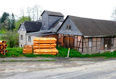 Die Alte Mühle im Heinsdorfer Ortsteil Hauptmannsgrün. Auf den ersten Blick könnte man denken, dort fänden in Kürze umfangreiche Bauarbeiten statt. Der Platz vor der Immobilie wird jedoch lediglich als Lagerfläche für den gerade laufenden Ausbau der Hauptstraße genutzt. 