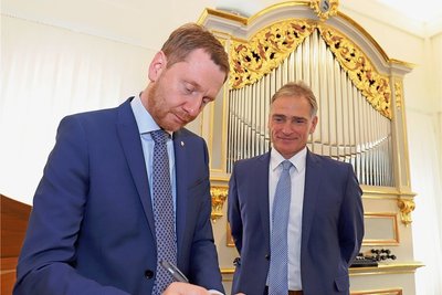 Unter den wachsamen Augen von Frauensteins Bürgermeister Reiner Hentschel (r.) trägt sich Ministerpräsident Michael Kretschmer als erster in das neue Gästebuch des Gottfried-Silbermann-Museums ein. 
