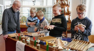 Unter Anleitung von AG-Leiter Wilfried Tomaszewski zeigten die jungen Schnitzer Louis Reichenbach, Domenic Götze, Henning Tränkner und Karl-Kurt Richter (von links) im Depot Pohl-Ströher ihr Können. In der Gelenauer Grundschule treffen sie sich einmal pro Woche, um gemeinsam zu üben. 