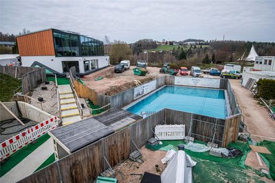 Ein Blick von der Terrasse des Badcafés auf das, was einerseits noch Baustelle, andererseits aber auch schon fertiggestellt ist, wie das Ruhehaus (links) und das Außenschwimmbecken.