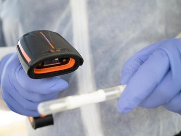            Ein Arzt in Schutzkleidung scannt ein Teststäbchen in einer mobilen Corona-Teststation.