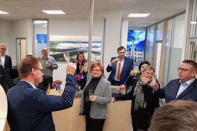 Regionalleiter Bastian Richter (links) hat am Freitagvormittag mit Mitarbeitern und Gästen das Glas auf die neue Filiale erhoben. Großformatige Fotos aus Oelsnitz und Umgebung sind Blickfang in den Räumen. 