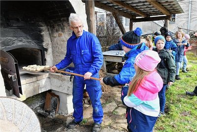 Tim Meyer schiebt die ersten Brötchen in den Backofen, die die Hortkinder aus Halsbrücke geformt haben. 