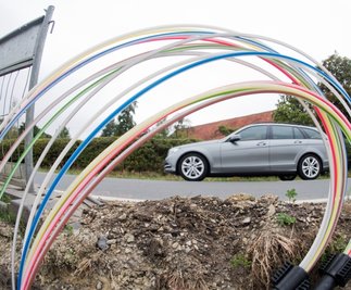 Ein Auto fährt an einer Baugrube vorbei, in der Leerrohre für Glasfaserleitungen für schnelles Internet liegen. In dieser Hinsicht gibt es in Stollberg erheblichen Nachholbedarf 