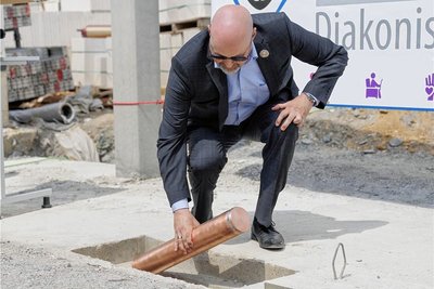 Uwe M. Junga, kaufmännischer Vorstand der Bethanien Diakonissen-Stiftung, versenkt die Zeitkapsel im Fundament.
