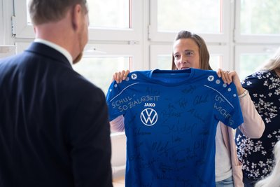 Franziska Illig überreicht Ministerpräsident Michael Kretschmer ein T-Shirt mit den Unterschriften zum Erhalt der Schulsozialarbeit.