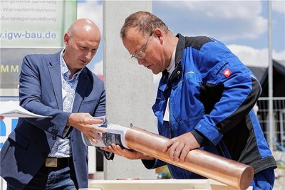 Scheibenbergs Bauamtsleiter André Bergmann steuerte zwei Amtsblätter und Kinderzeichnungen der Baustelle bei. Klempner Sven Rieger (r.) verschloss die Kapsel anschließend fachgerecht.