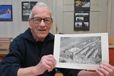 Wilfried Schließer heute. Er zeigt ein Bild, auf dem das Wohnviertel in der Dresdner Altstadt vor der Bombardierung zu sehen ist.