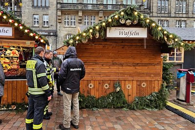 Mitarbeiter der Feuerwehr, der Marktleitung und der Polizei haben sich am Freitag vor dieser Bude eingefunden.