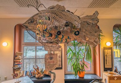 Hängt in der Galerie: ein riesiger Fisch aus gebrauchten CDs, der für den Schutz der Gewässer wirbt.