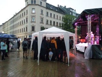 Um sich vor dem Regen zu schützen, stellten Gäste spontan einen Pavillon vor die Bühne.