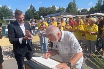 Jürgen Beyer trägt sich zur Eröffnung des Badfestes in das Goldene Buch der Gemeinde Neukirchen ein.