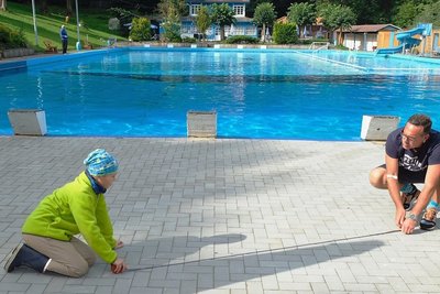 Hier soll das neue Planschbecken hin. Fördervereinsvorsitzender Matthias Kolbe misst den Platz mit Sohn Linus Weißer schon mal aus.