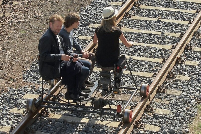 Das wird im achten Erzgebirgskrimi des ZDF nicht zu sehen sein: Der von Kai Scheve (l.) gespielte Kommissar rollt auf einem Schienenfahrrad über das Gelände des Eisenbahnmuseums in Schwarzenberg. 