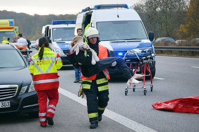 Ein Feuerwehrmann trägt ein Kind über die Autobahn 4.