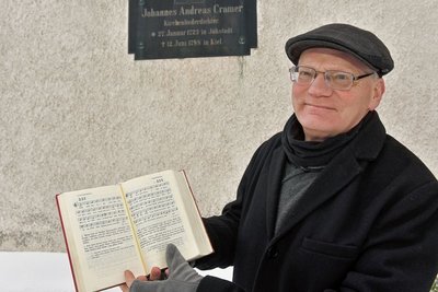 Der Jöhstädter Kantor Andreas Rockstroh würdigt den Theologen und Schriftsteller, an den in seiner Geburtsstadt eine Tafel am Kirchenschiff erinnert. Zudem zeigt er das Gesangsbuch der evangelischen Christen, in dem unter Nummer 221 ein noch heute gesungenes Lied aus der Feder Cramers vermerkt ist. 