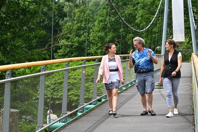 Nadine Gläser von der Sparkasse Mittelsachsen, Stephan Lazarides vom Heimatverein Auerswalde/Garnsdorf und Sylvia Zimmer vom Jugendtreff „Haus Kontakt“ (von links) auf der Hängebrücke am Chemnitztalradweg.