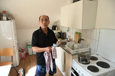 Pham Phi Son wie er in der Küche steht und einen Teller abtrocknet.