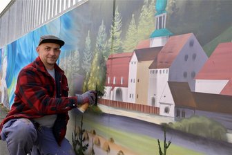 27 Meter langes Wandbild entsteht im Erzgebirge und erinnert an Tradition in Bergbau und Hüttenwesen - Die Stützwand am Albernauer Dorfplatz wird derzeit von Alexander Mehlhorn gestaltet. Unter anderem dort zu sehen das Blaufarbenwerk, wie es um 1845 ausgesehen hat.