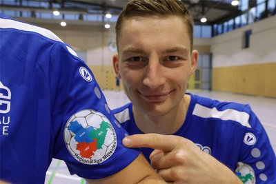 Kapitän Sebastian Poppitz zeigt das Logo der Regionalliga Mitteldeutschland auf den Trikots des HC Glauchau/Meerane.